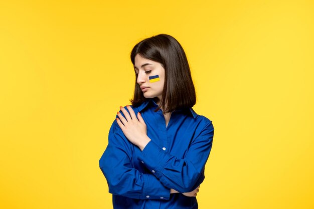 Ukraine russian conflict brunette pretty cute girl with flags on cheeks embracing shoulders