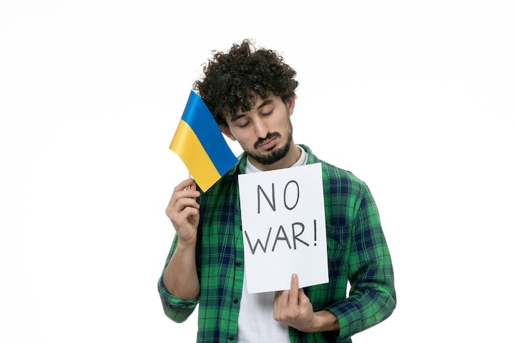 Бесплатный Фотография украинский русский конфликт милый парень в зеленой рубашке с табличкой "нет войны" и украинским флагом