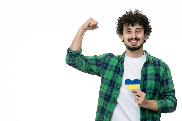 Ukraine russian conflict cute young guy in green shirt holding ukrainian heart showing strength