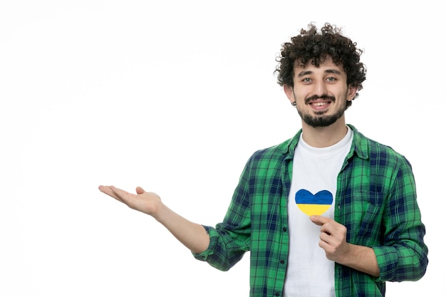 Ukraine russian conflict cute young guy in green shirt holding ukrainian heart waving hands