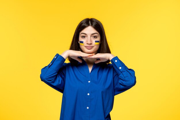 Ukraine russian conflict dark hair cute girl with flags on cheeks making pretty face