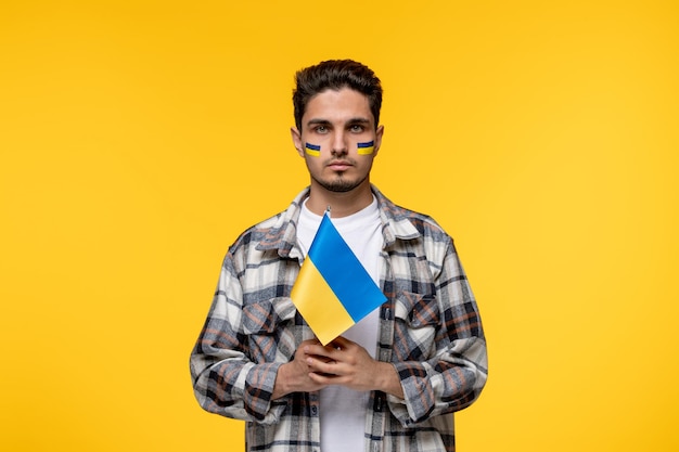 Ukraine russian conflict handsome courageous guy with flags on cheeks holding ukrainian flag