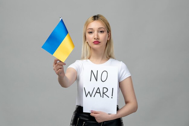 Ukraine russian conflict young cute girl holding no war sign and ukrainian flag serious