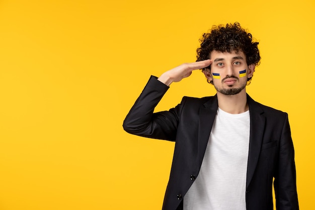 Ukraine russian conflict young guy in blazer painted ukrainian flag on face serving gesture