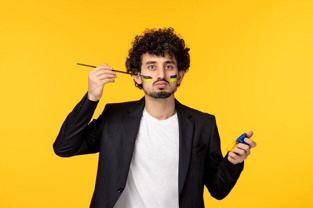 Ukraine russian conflict young guy in blazer painting ukrainian flag on face blue yello paints