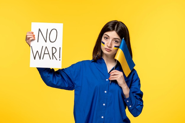 Ukraine russian conflict young pretty girl in blue shirt yellow background holding no war sign