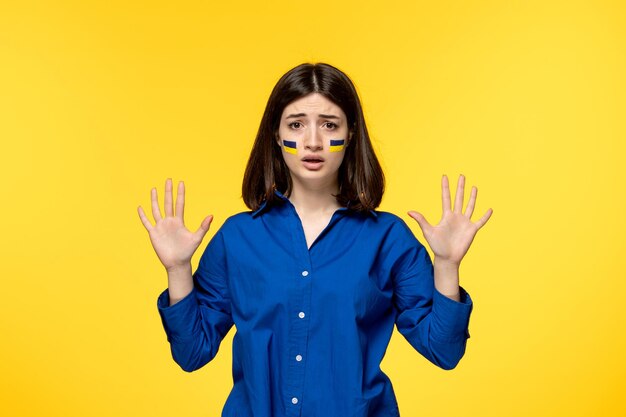 Free photo ukraine russian conflict young pretty girl flags on cheeks yellow background saying to stop