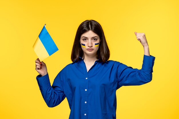 Ukraine russian conflict young pretty girl flags on cheeks yellow background showing strength