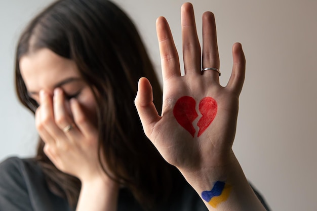 Ukrainian girl with a broken heart drawn on her hand pain for ukraine