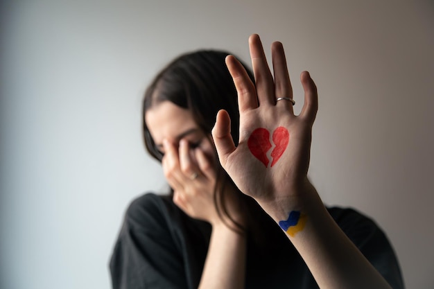 Free photo ukrainian girl with a broken heart drawn on her hand pain for ukraine