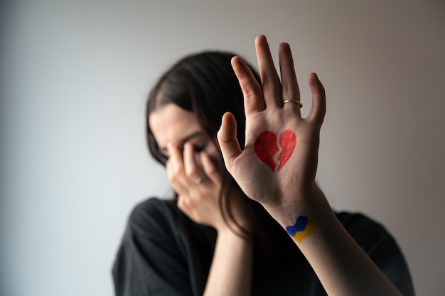 Ukrainian girl with a broken heart drawn on her hand pain for ukraine