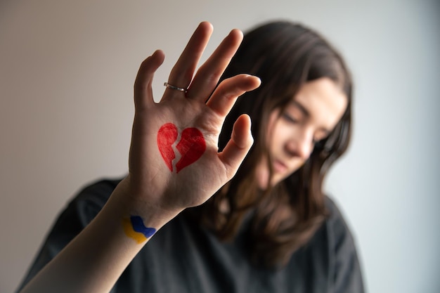 Ukrainian girl with a broken heart drawn on her hand pain for ukraine