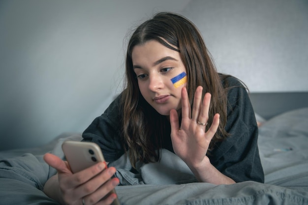 A ukrainian woman with a painted flag on her face communicates via video link