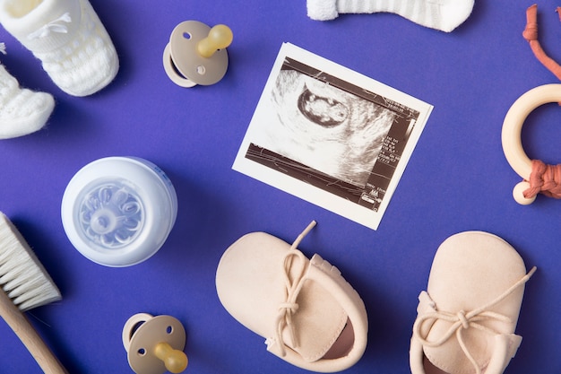 Immagine ad ultrasuoni con ciuccio; spazzola; bottiglia di latte; paio di scarpe e giocattoli su sfondo blu