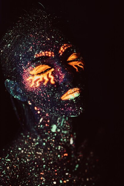 Ultraviolet make-up. Portrait of a girl painted in fluorescent powder. Halloween concept.