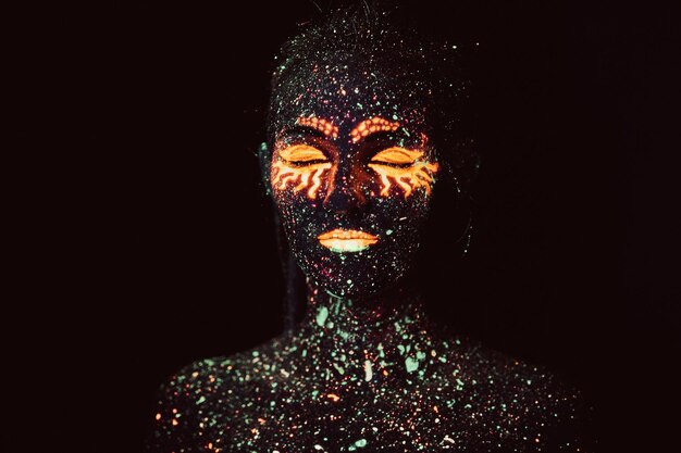 Ultraviolet make-up. Portrait of a girl painted in fluorescent powder. Halloween concept.