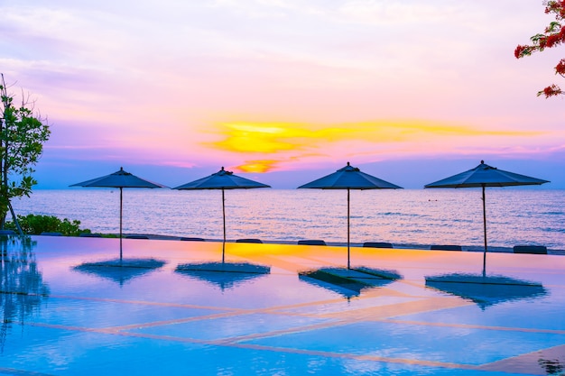 Free photo umbrella and chair around swimming pool neary sea ocean beach at sunrise or sunset time