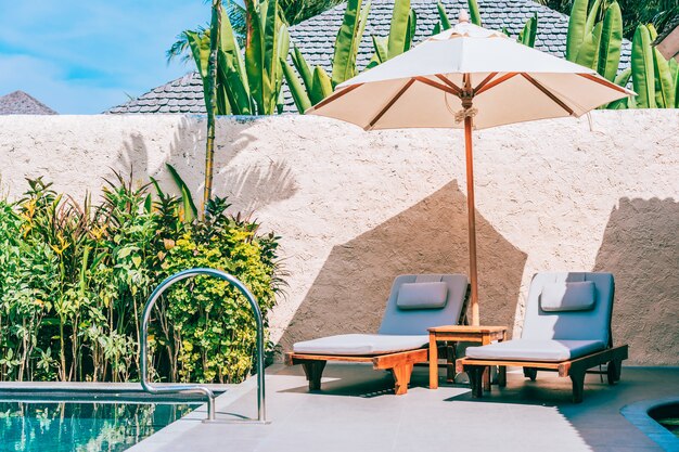 Umbrella and chair around swimming pool neary sea ocean beach with blue sky and white cloud