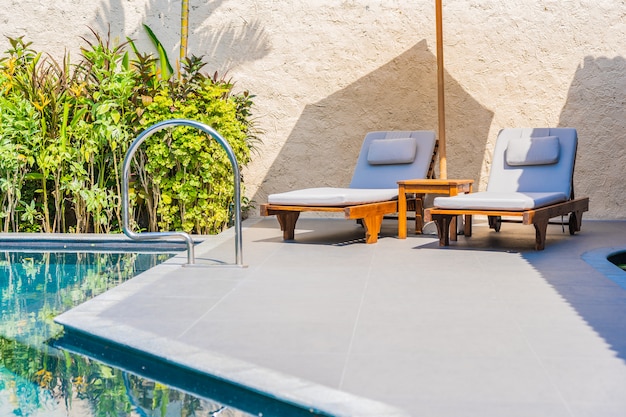 Free photo umbrella and chair around swimming pool neary sea ocean beach with blue sky and white cloud