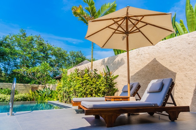 Free photo umbrella and chair around swimming pool neary sea ocean beach with blue sky and white cloud