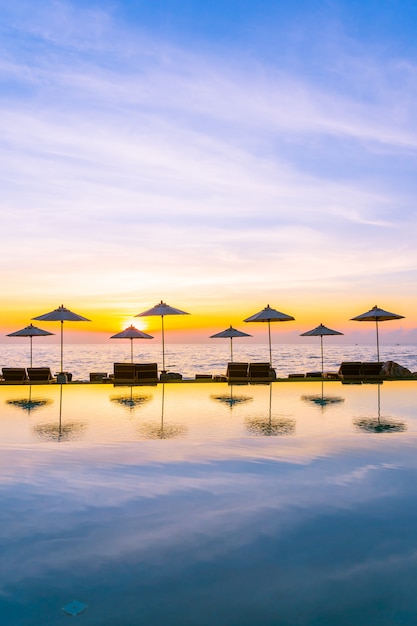 Foto gratuita ombrello e sedia intorno alla piscina in hotel resort per viaggi di piacere e vacanze