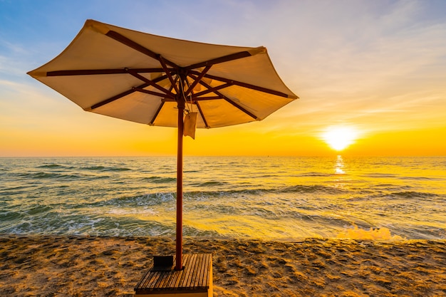 Зонтик и стул с подушкой вокруг красивого пляжа и моря