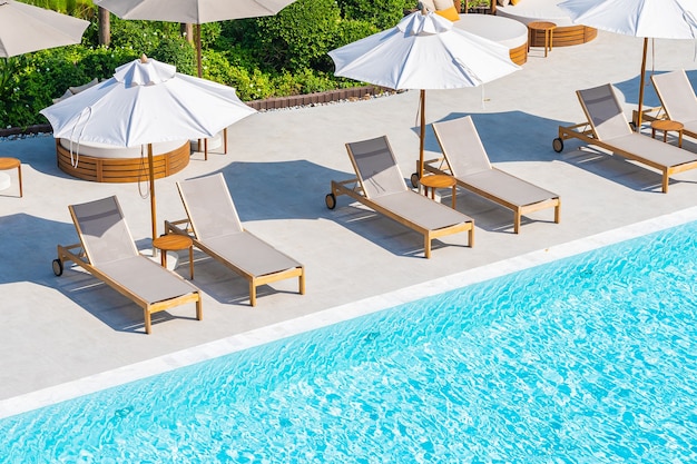 Зонтик и шезлонг вокруг открытого бассейна в курортном отеле недалеко от моря, пляжа, океана