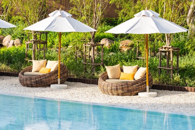 바다 바다 해변과 코코넛 야자 나무가있는 호텔 리조트의 야외 수영장 주변의 우산과 갑판 의자