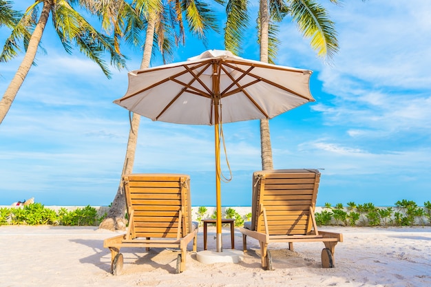 Umbrella and deck chair around outdoor swimming pool in hotel resort with sea ocean beach and coconut palm tree