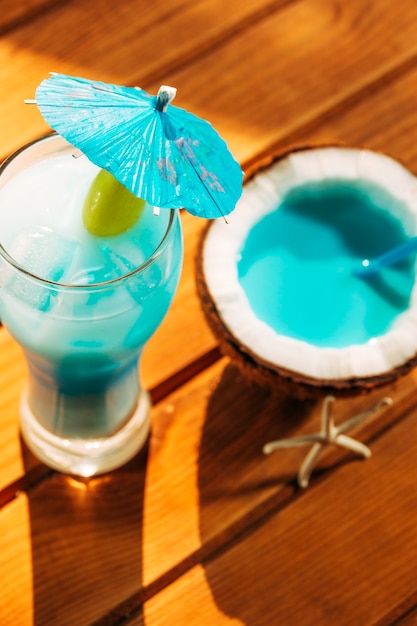 傘装飾ガラスと明るい青の飲み物とひびの入ったココナッツ