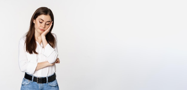 Free photo unamused bored brunette woman looking gloomy and sad sighing standing reluctant over white backgroun