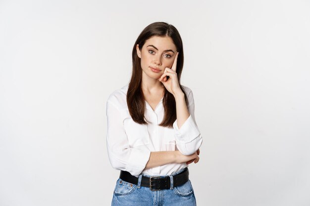 Unamused bored brunette woman looking gloomy and sad sighing standing reluctant over white background