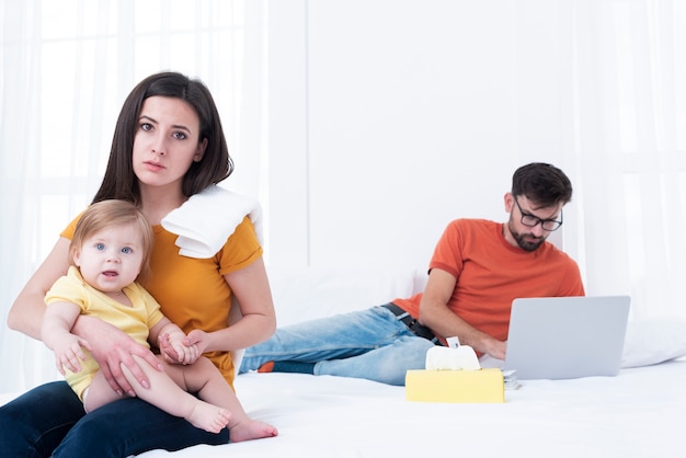 Unamused mother holding baby on her lap