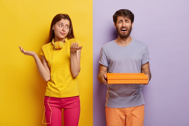 Unaware questioned girl spreads palms with hesitation, has no idea what is in box