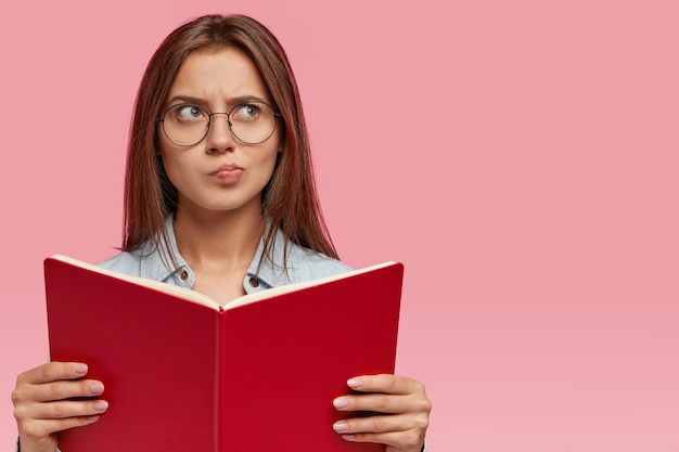 Uncertain brunette woman purses lips and has doubtful facial expression