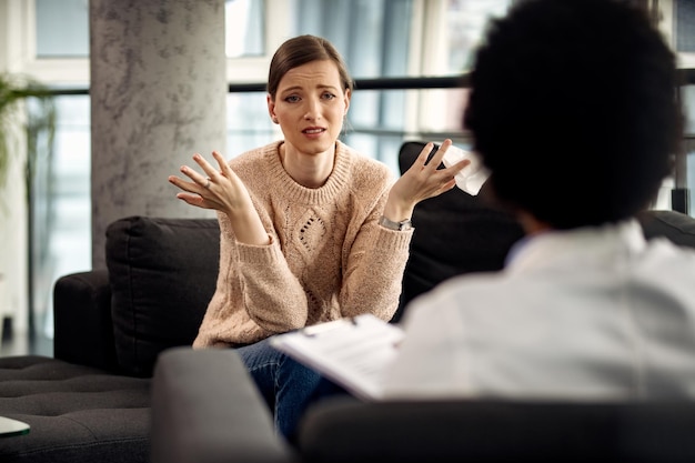 Uncertain woman communicating with her psychotherapist at doctor's office