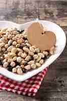 Free photo uncooked assorted legumes in heart shape plate on rustic wooden table.