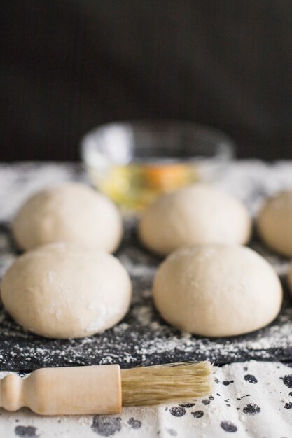 Uncooked bread dough with brush against black background