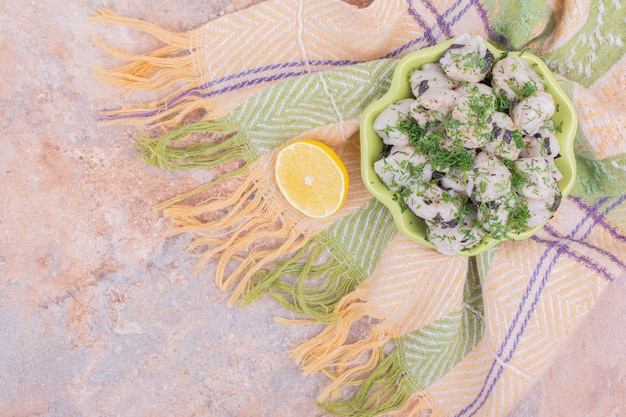 Uncooked caucasian khinkali in a bowl with chopped herbs