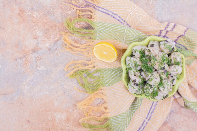 Uncooked caucasian khinkali with chopped herbs in a bowl.