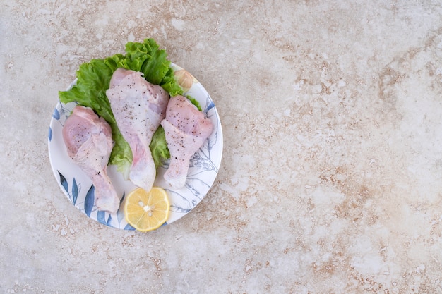 Free photo uncooked chicken legs meat with lettuce and lemon