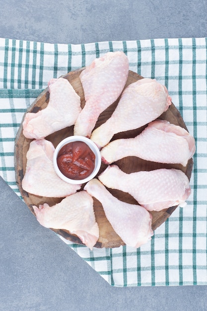 Free photo uncooked chicken legs and wings on wood piece.