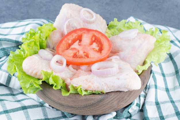 Uncooked chicken wings on wooden board.