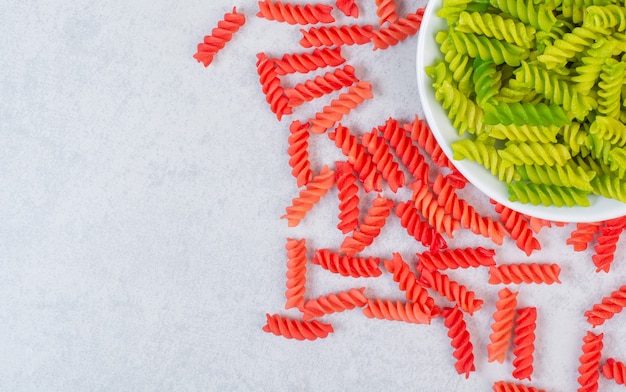 Foto gratuita pasta a spirale secca colorata cruda su una pietra.