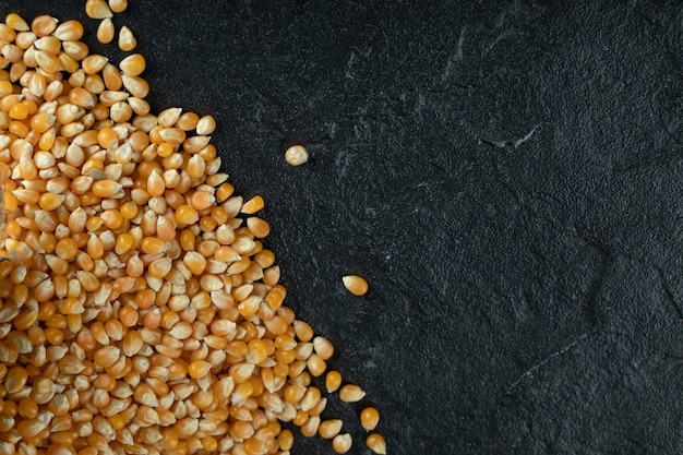 Uncooked corn grains on black.