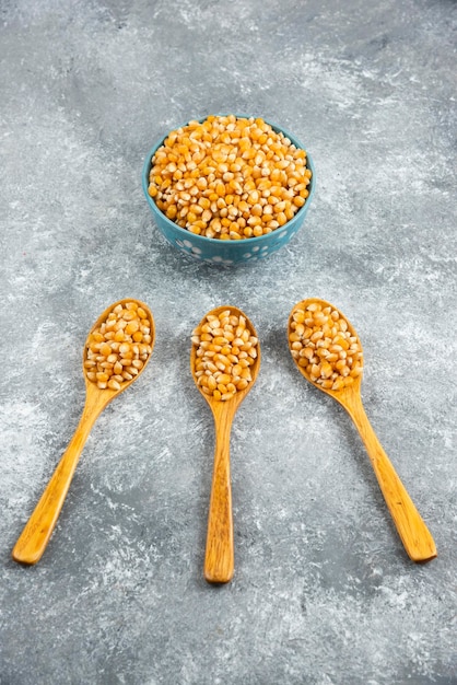 Free photo uncooked corn kernels in spoons and bowl.