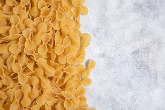 Pasta secca cruda di farfalle disposta sulla tavola di marmo. foto di alta qualità