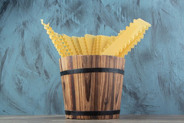 Free photo uncooked dry pasta in wooden bucket