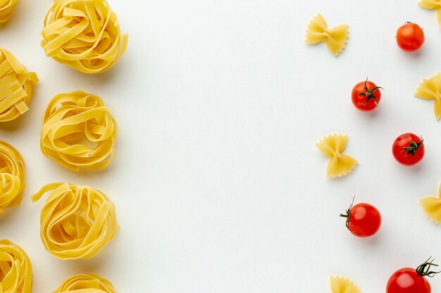 Uncooked farfalle and tagliatelle arrangement with tomatoes