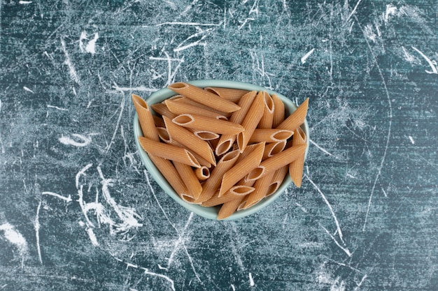 Uncooked fresh macaroni on blue plate 